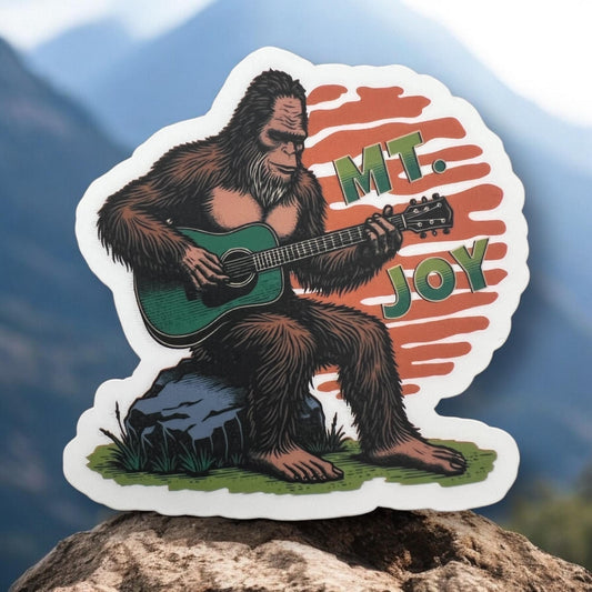 Mt. Joy Bigfoot Playing Green Guitar Orange Sitting on Rock Sunset Vinyl Sticker Slap 3" x 3" Matte Finish