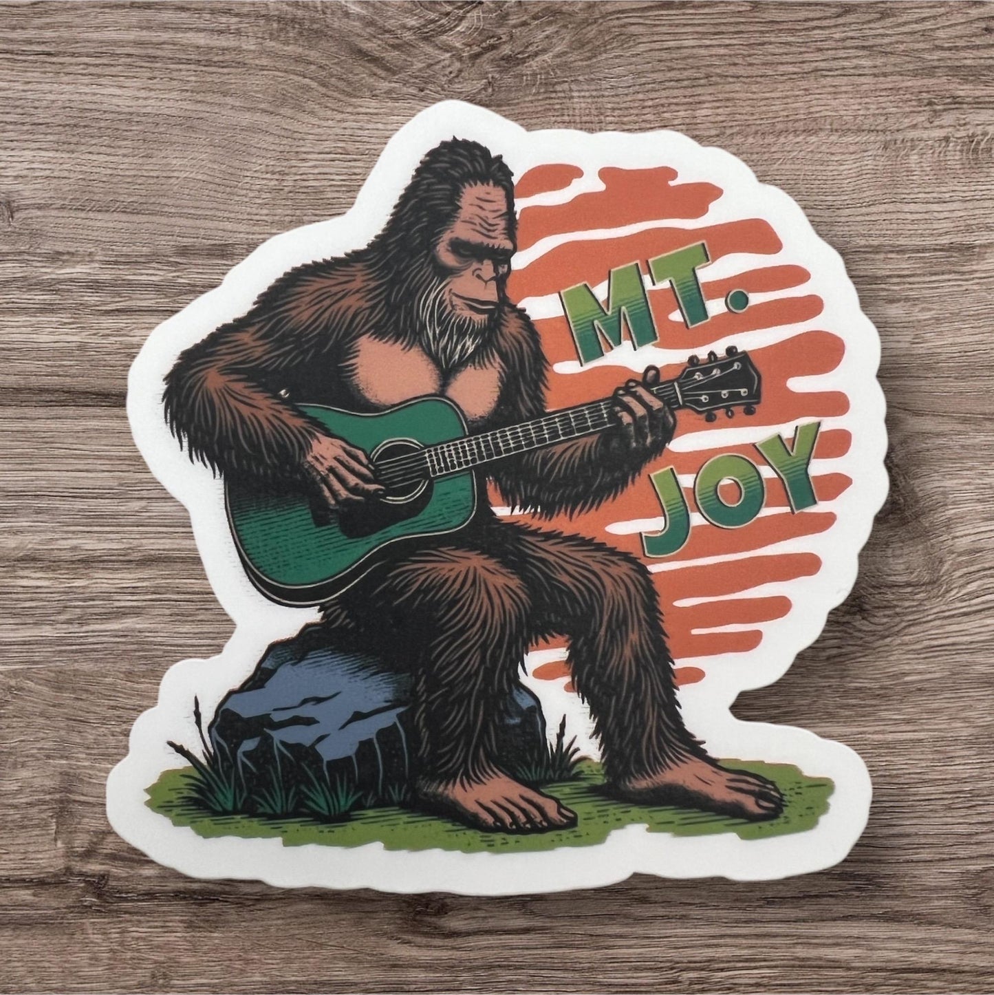 Mt. Joy Bigfoot Playing Green Guitar Orange Sitting on Rock Sunset Vinyl Sticker Slap 3" x 3" Matte Finish